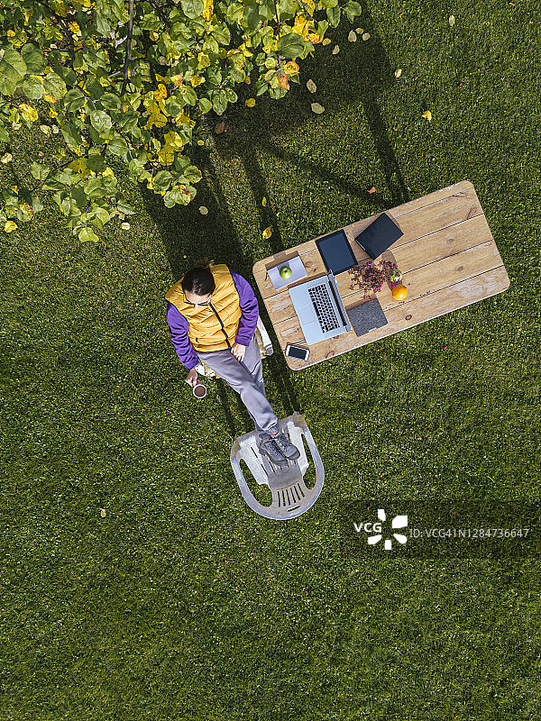 在花园里边工作边喝咖啡的女人图片素材