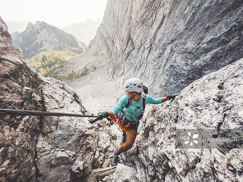 女登山者攀登铁索栈道图片素材