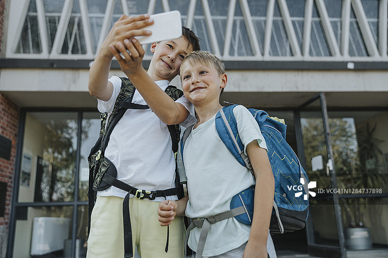 兄弟俩在学校大楼前用智能手机自拍图片素材