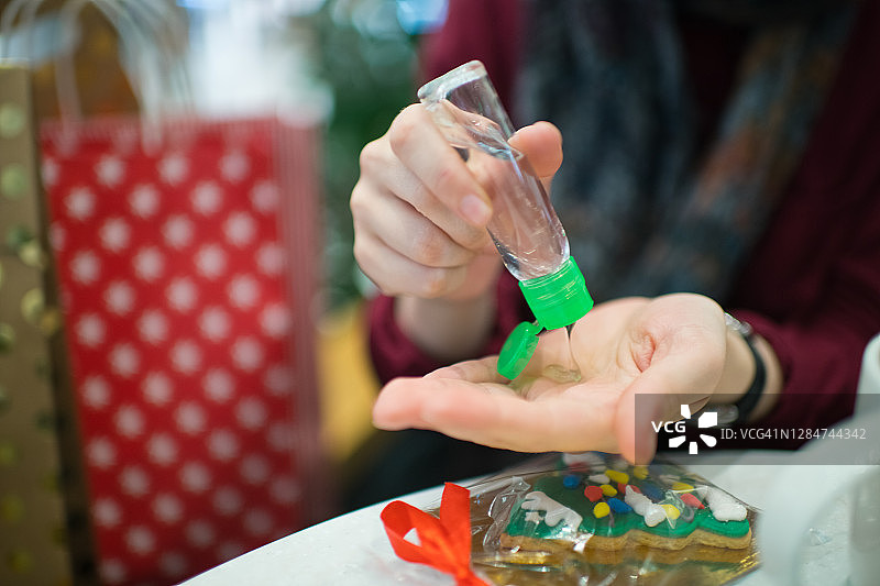 年轻女人在圣诞购物期间的咖啡馆里使用免洗洗手液图片素材