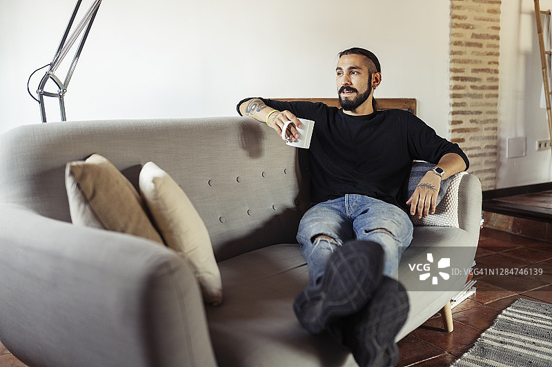 男人在家坐在沙发上手拿咖啡杯图片素材