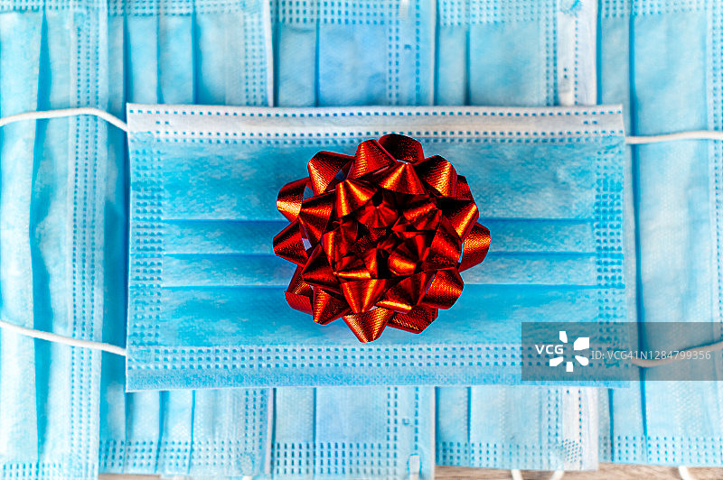 礼物概念——面部防护口罩上的红色蝴蝶结图片素材