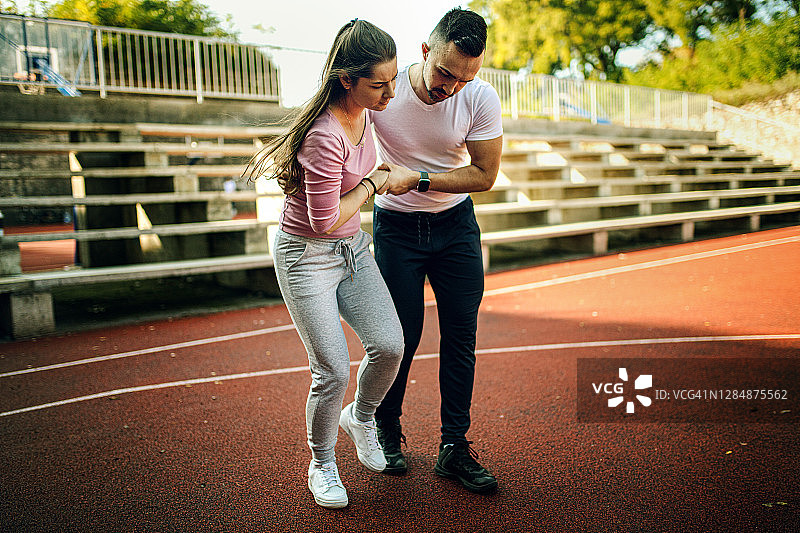 健身教练帮助受伤的年轻女子图片素材