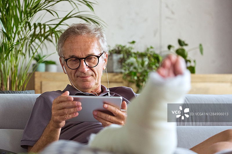 腿部骨折的老年男人在家中图片素材