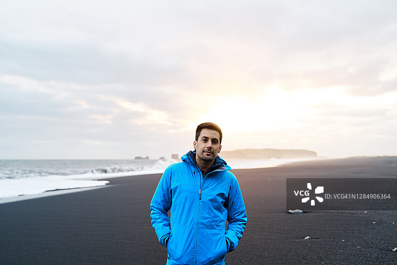 身穿保暖服装的年轻男子站在暴风雨中的海边图片素材