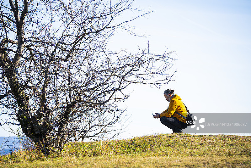 中年男人在山顶操控无人机拍摄视频照片图片素材