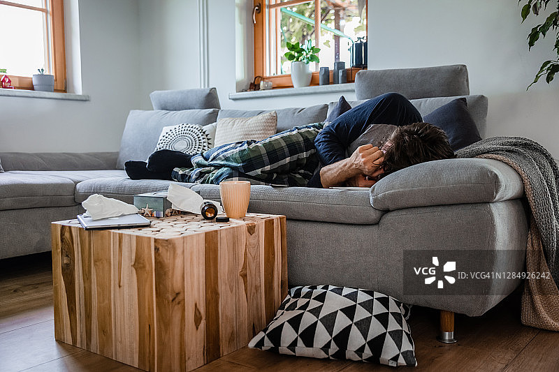 生病的男人躺在家里沙发上图片素材