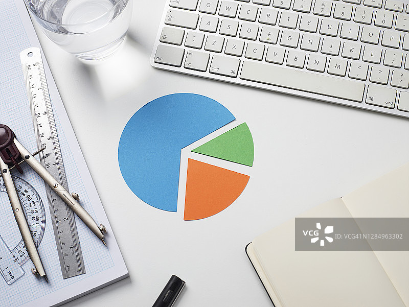 白色桌面上的电脑键盘和带有饼图的鼠标垫图片素材