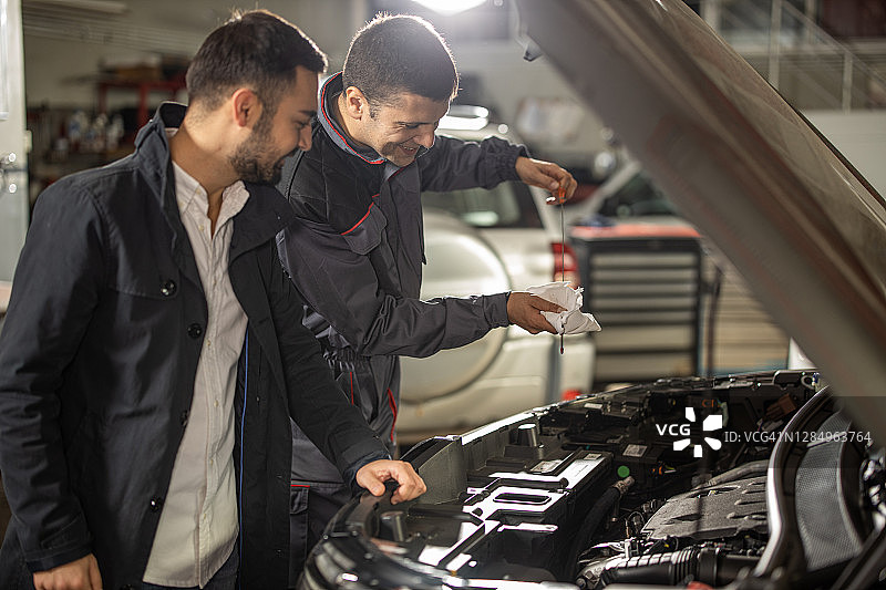 在汽车修理店与修理工在一起的年轻男人图片素材