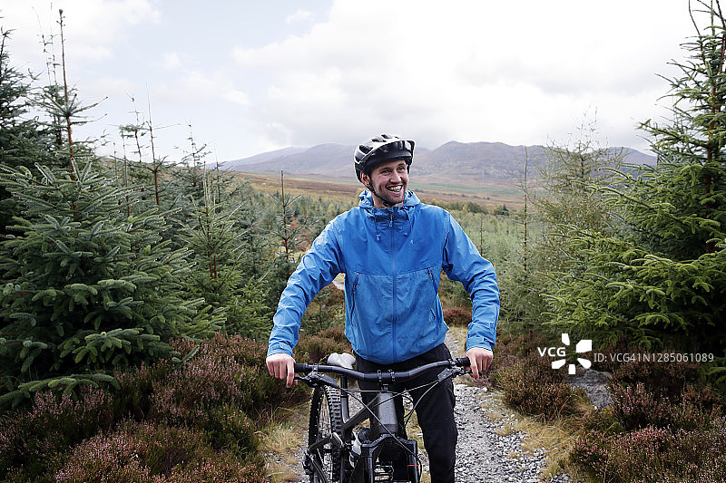 快乐的男性山地自行车手站在自行车旁图片素材