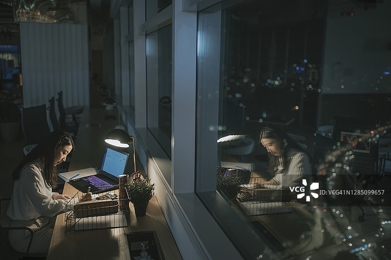 在办公室深夜赶金融报告的亚洲女白领图片素材