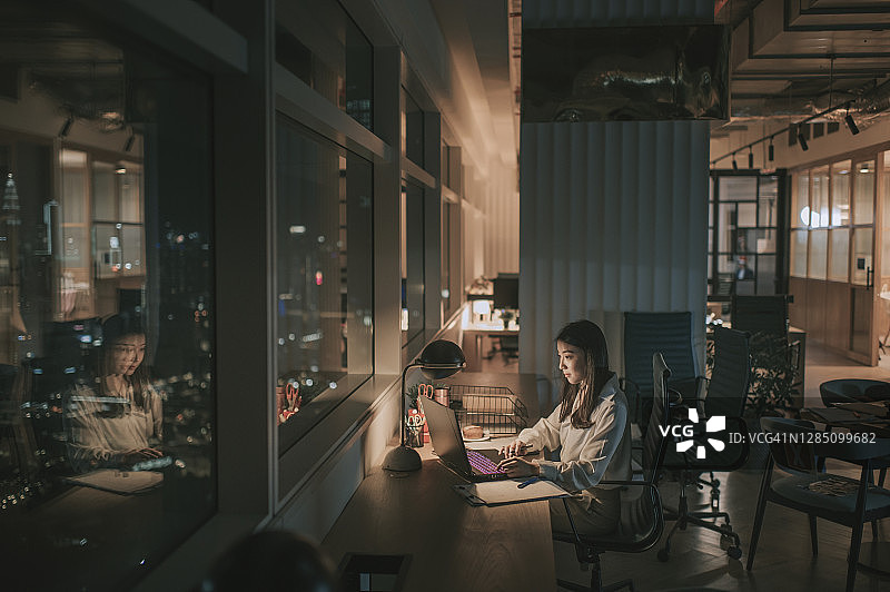 在办公室深夜赶金融报告的亚洲女白领图片素材