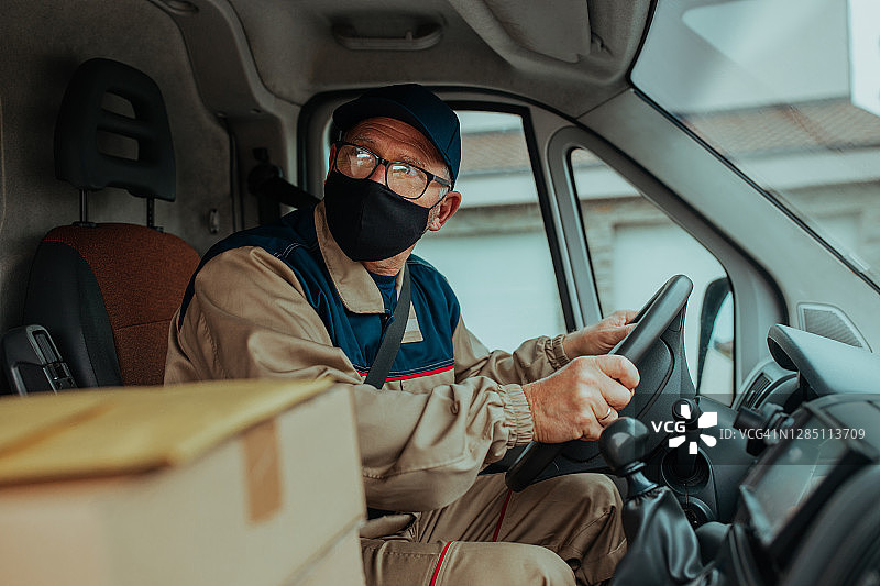 戴着口罩的邮递员向顾客递送包裹图片素材