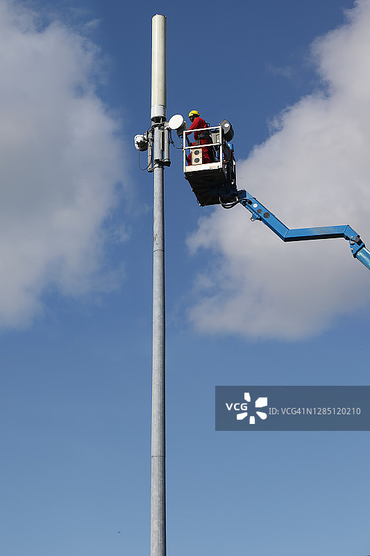 男人在高高的电话杆上工作图片素材