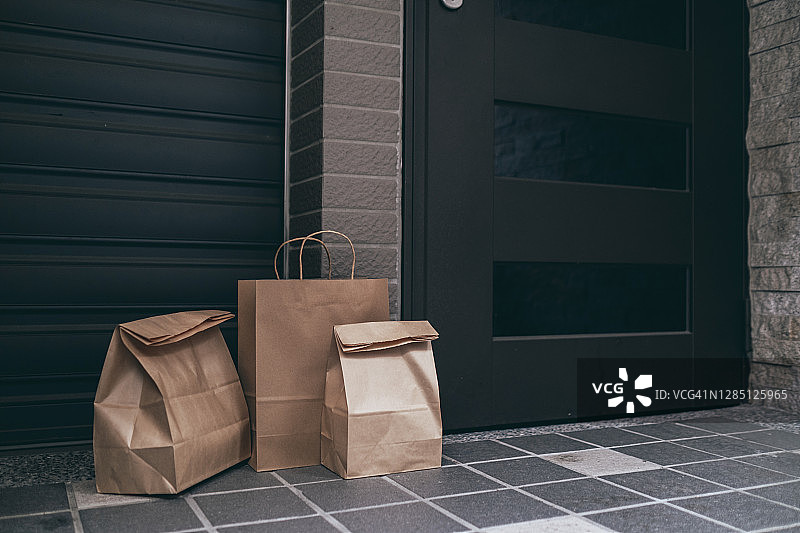 外卖餐品：装在棕色纸袋中，送至住宅楼前门图片素材