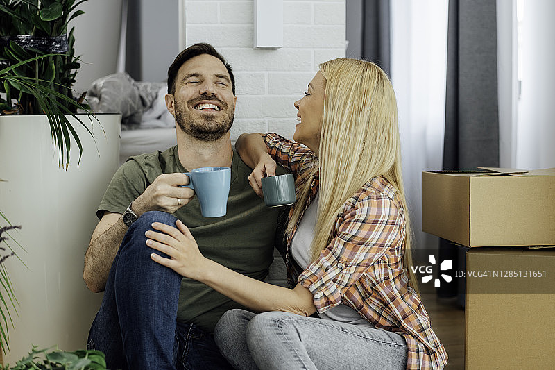 面带笑容的情侣搬家休息时喝咖啡图片素材