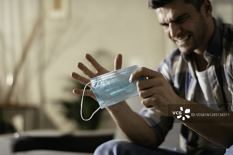 手里拿着防护口罩的年轻男子图片素材