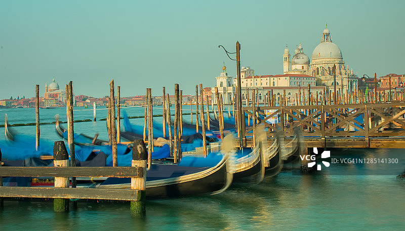 系在码头柱子上的意大利贡多拉，远处是威尼斯大教堂图片素材