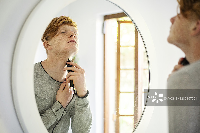 青少年在家用电动剃须刀刮胡子图片素材