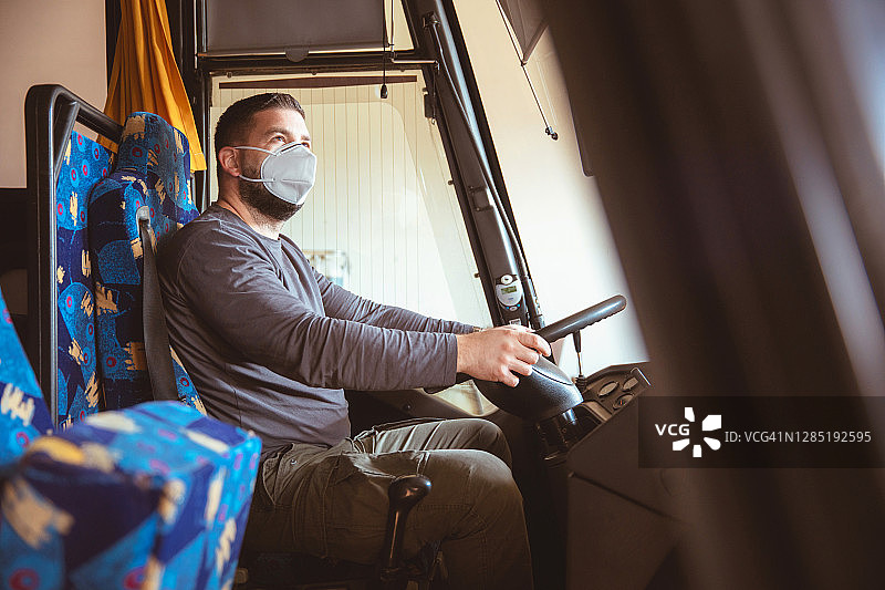 身穿白色防护服戴口罩的专业公交车司机图片素材