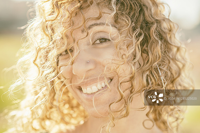 户外，头发遮面的快乐微笑女人看着镜头图片素材