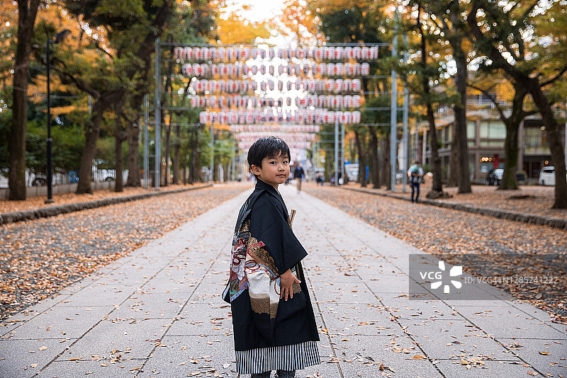 穿着日式和服袴的小男孩在街上为“七五三”仪式回头看图片素材