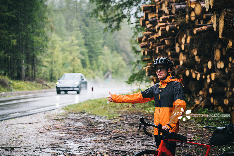 骑自行车的男人在湿滑路边搭便车图片素材