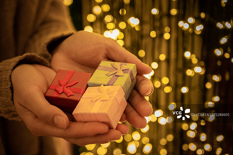 手持一小组包装好的礼品盒，带有美丽的散景光图片素材