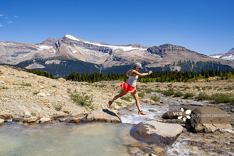 越野跑女人跳过高山溪流图片素材