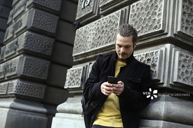 在街上使用手机App的西班牙裔男子图片素材