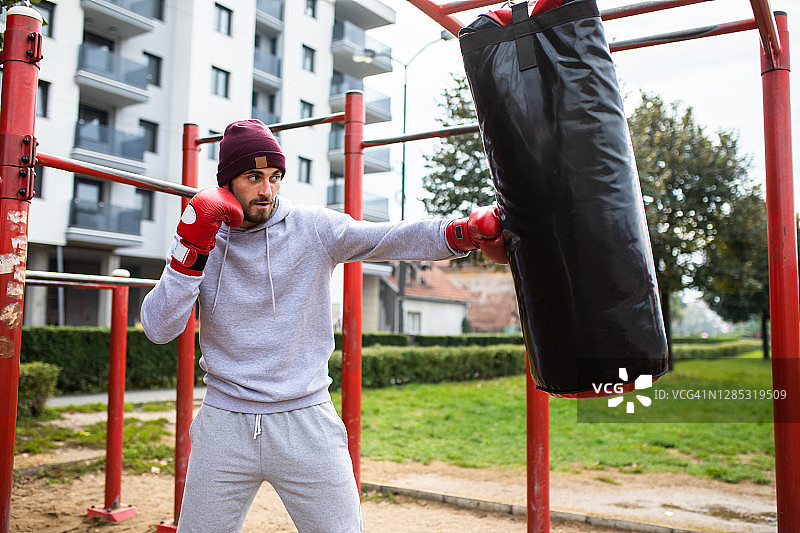 在户外击打重沙袋的迷人男人图片素材