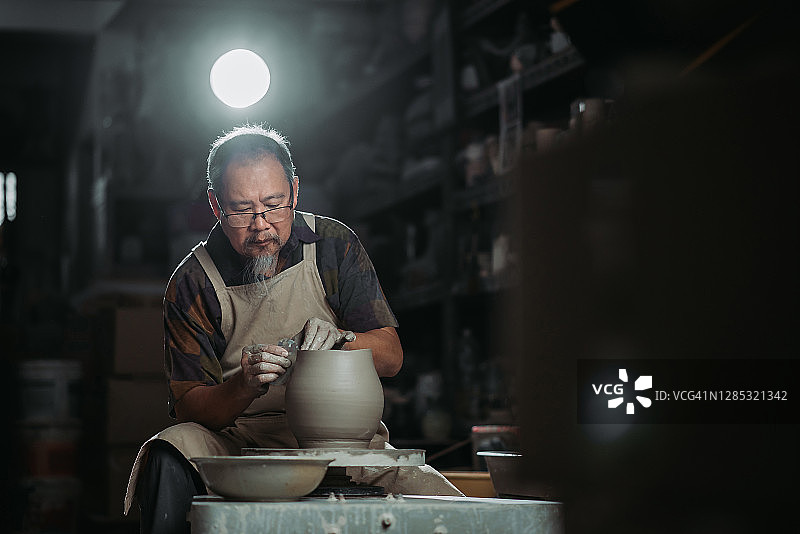 年长的华人陶艺家在工作室用陶轮制作陶器图片素材