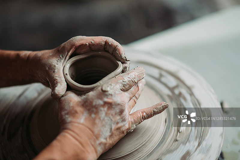 年长的华人陶艺家在工作室用陶轮制作陶器图片素材
