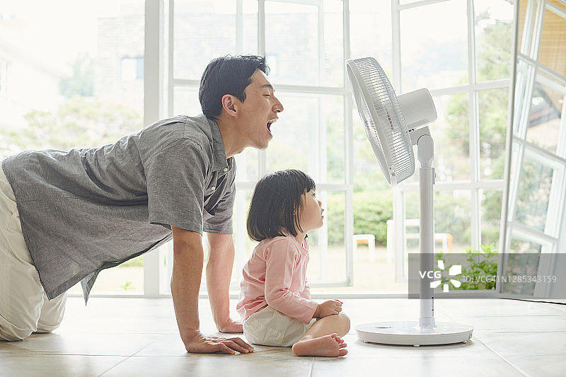 父亲和女儿享受风扇带来的凉风图片素材