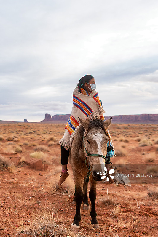 戴着口罩的年轻纳瓦霍族少女骑在马背上图片素材