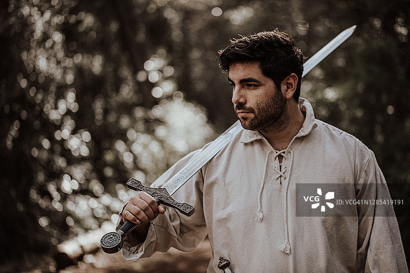 身着古装的年轻男子肩扛宝剑的黑暗肖像图片素材