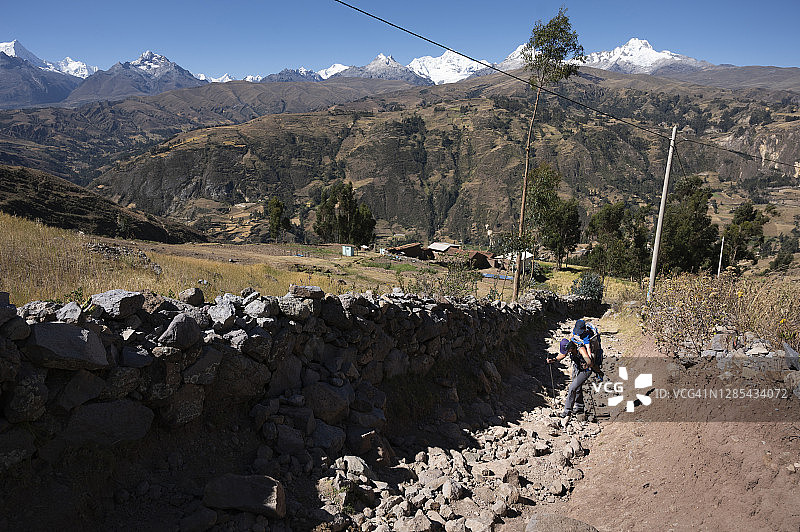 一位母亲背着孩子在古老的道路上徒步旅行图片素材