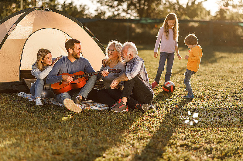 快乐的大家庭在野外露营时享受吉他音乐图片素材