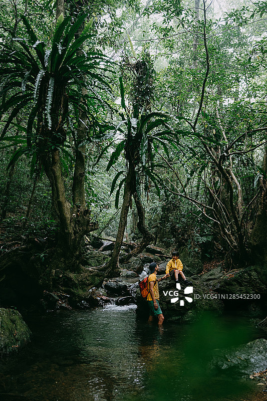 年轻女孩和父亲在丛林里的河边图片素材