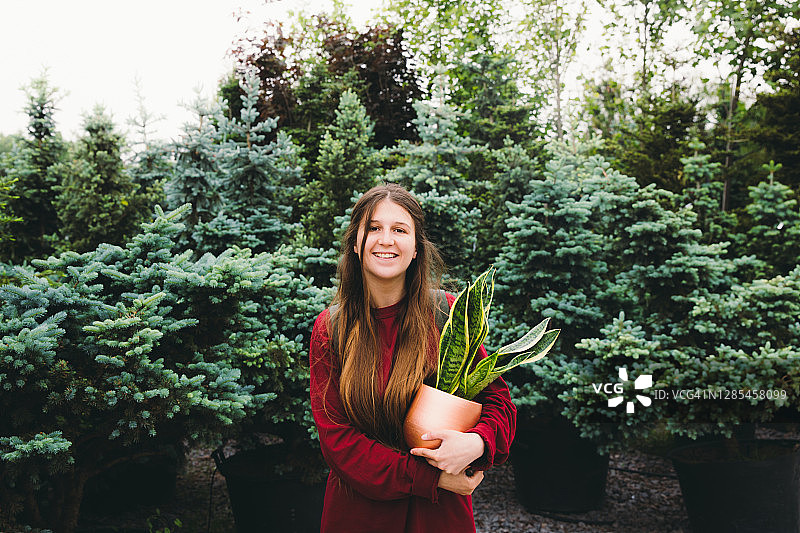 年轻女人很高兴买新植物回家图片素材