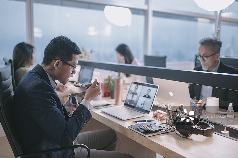 在办公室视频通话中用餐的亚洲商人图片素材
