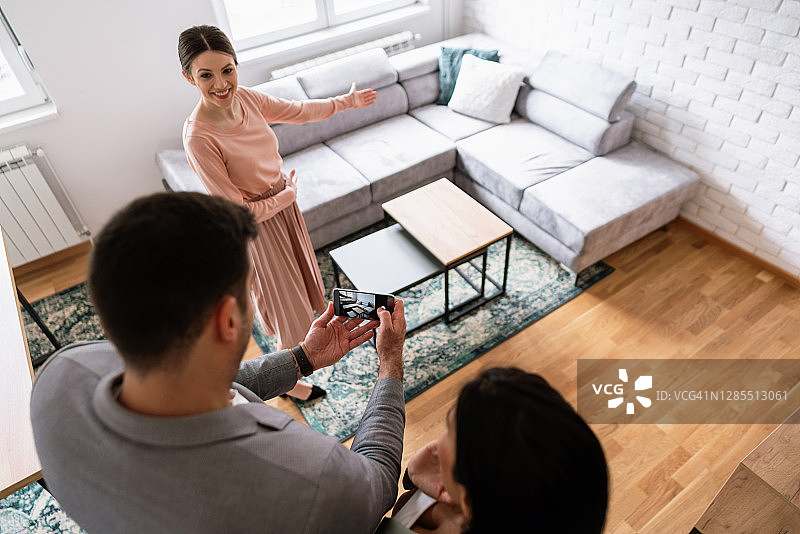 女房产经纪人展示新公寓，年轻男子用手机拍摄房屋细节图片素材