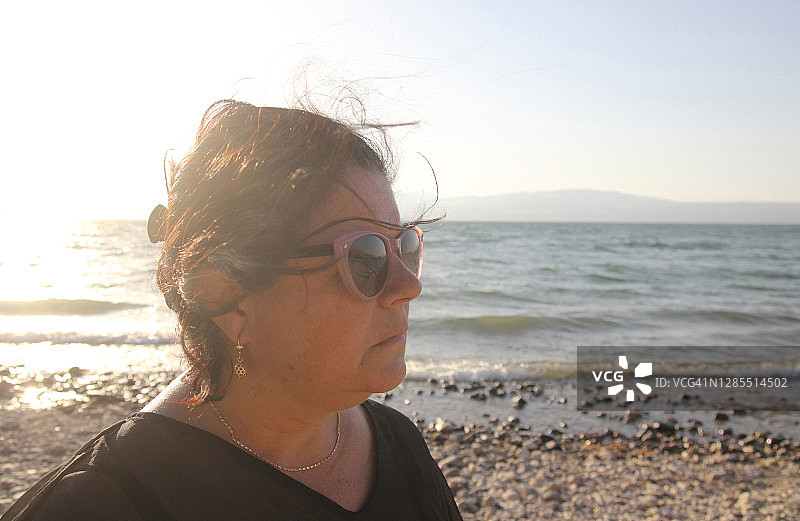 年长的妇女在海滩上欣赏日落图片素材