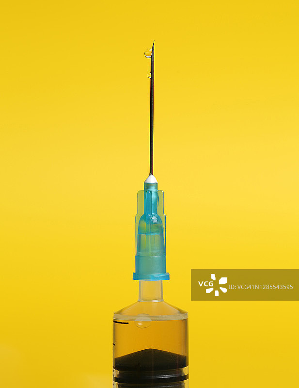 黄色背景上的注射器针头特写 - 新型冠状病毒 Covid-19 疫苗图片素材