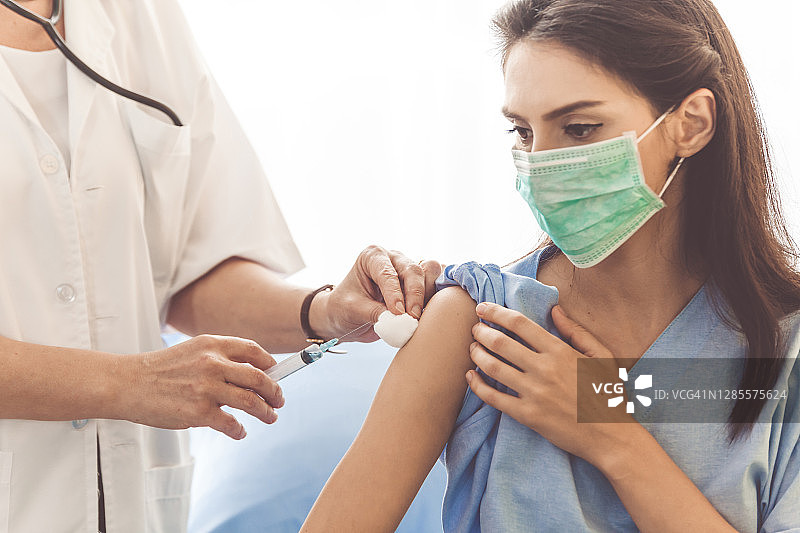 医生给病人接种疫苗、流感疫苗或用针头抽血。护士进行注射或使用注射器。英俊成熟的医生戴着防护手套为女性注射的局部照片图片素材