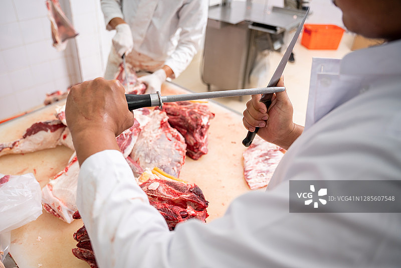 屠夫用刀切割牛肉特写图片素材