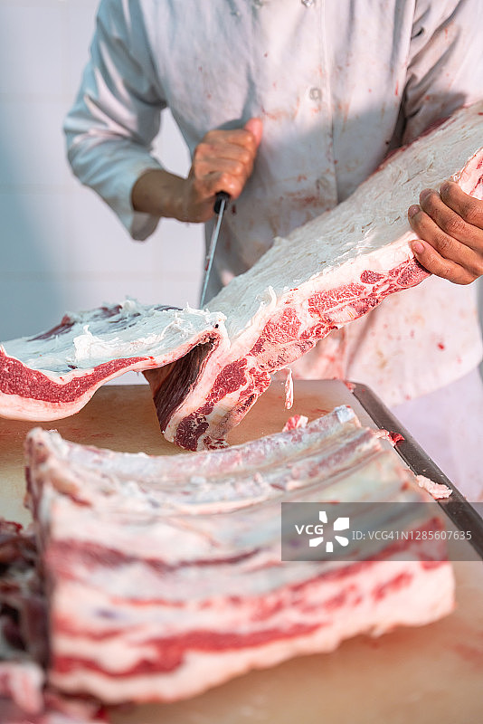屠夫用刀切割牛肉特写图片素材