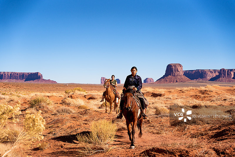 骑着马的年轻纳瓦霍族兄弟姐妹，背景是纪念碑谷图片素材