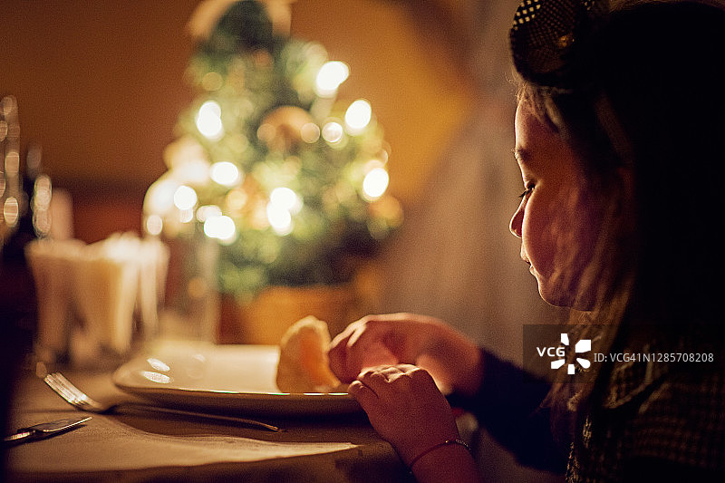 圣诞之夜独自吃饭的孤独悲伤小女孩图片素材
