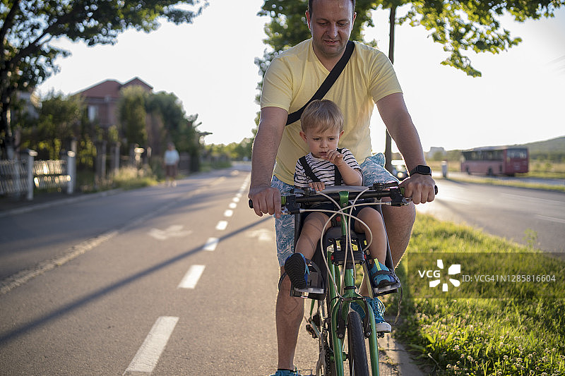 父亲用儿童座椅带着儿子骑自行车图片素材
